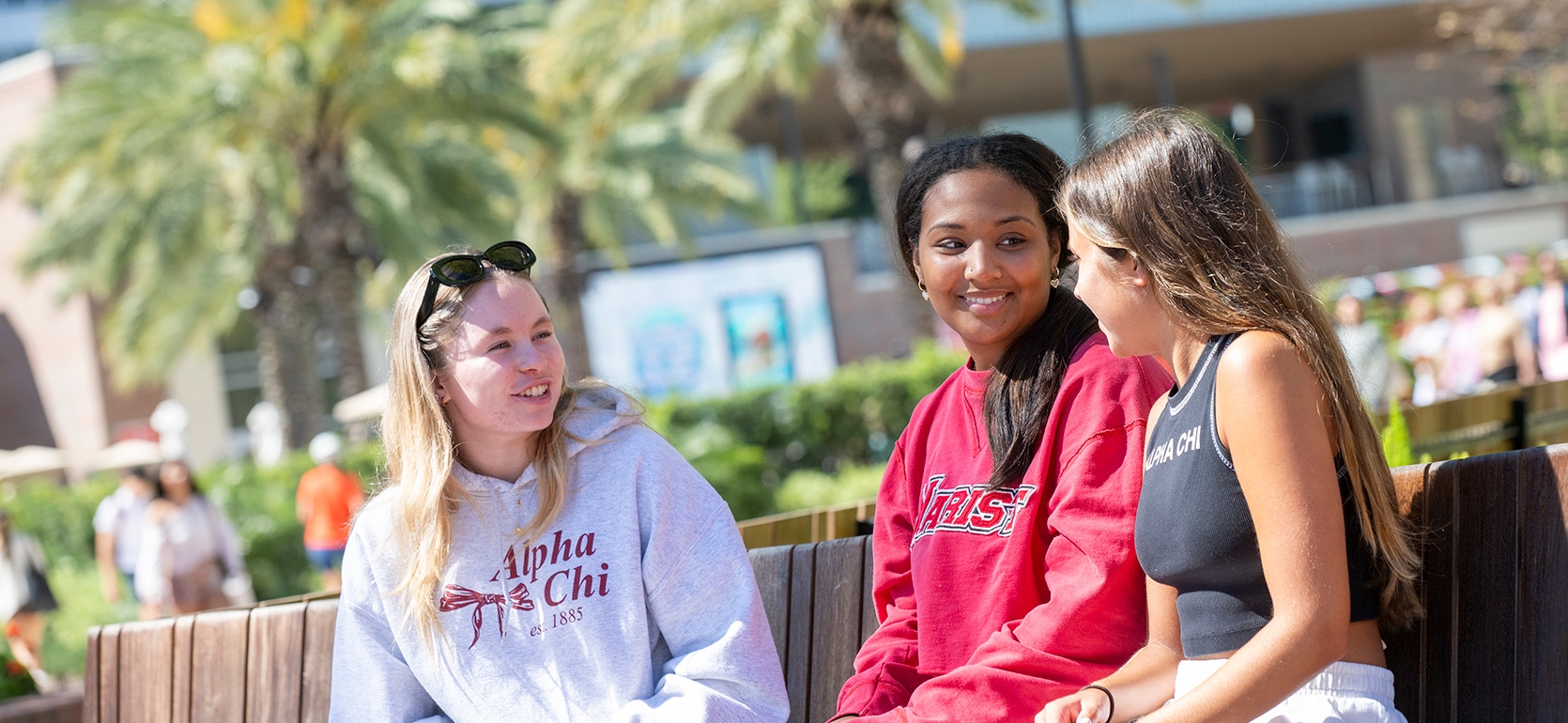 Three students talking on a bench in Sykes Plaza.